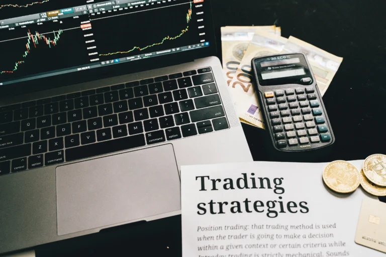 A laptop displays trading charts alongside currency notes, coins, and a document on strategies—illustrating how AI in Cryptocurrency Trading enables smarter risk management and faster execution for modern investors.