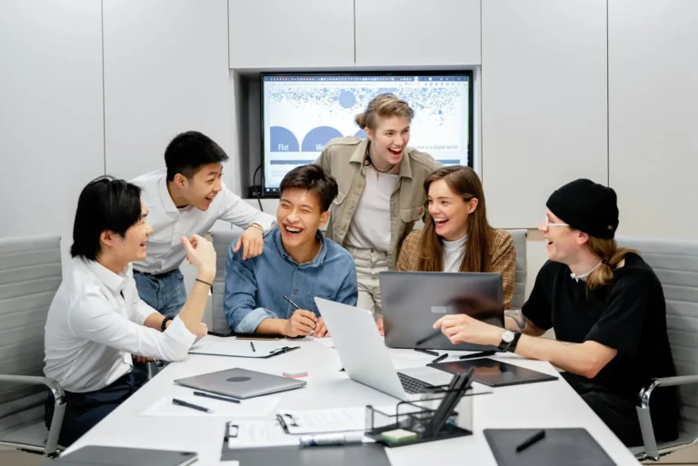 Team members engaged in a collaborative work session around a conference table, representing async collaboration practices that support global teamwork without burnout.