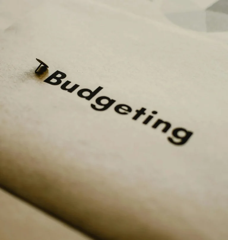 A push pin secures a paper labeled “Budgeting,” symbolizing Budget Allocation as a foundational framework for growth and resilience in financial planning and strategic decision-making.