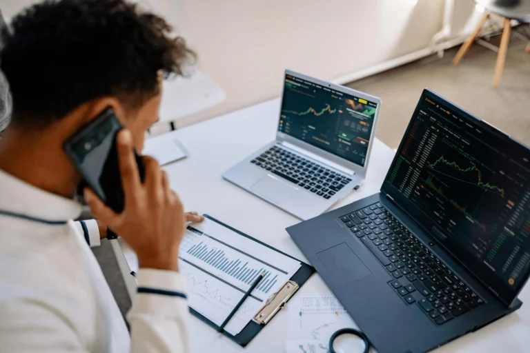An investor reviews charts and trading platforms on laptops, symbolizing financial analysis and the impact of CRM Stock in 2026 as Salesforce’s AI push meets market volatility.