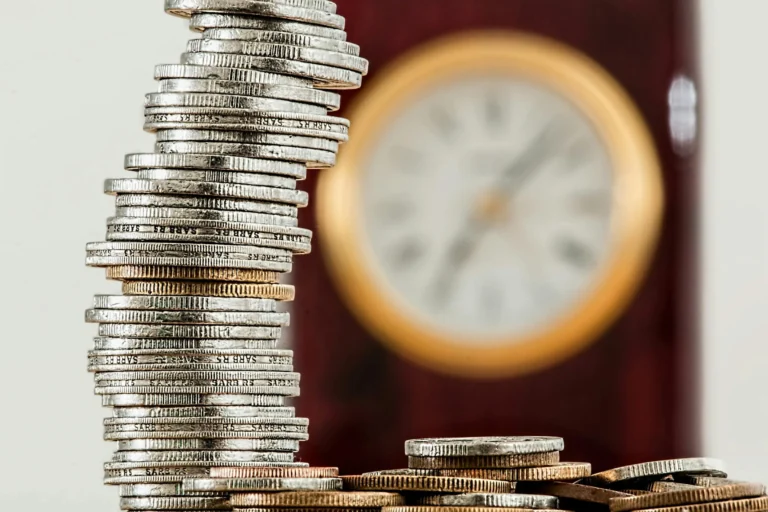 A leaning stack of coins with a clock in the background symbolizes the hidden costs of inefficient Data Entry Business Services and the need for fixes to save time and money.