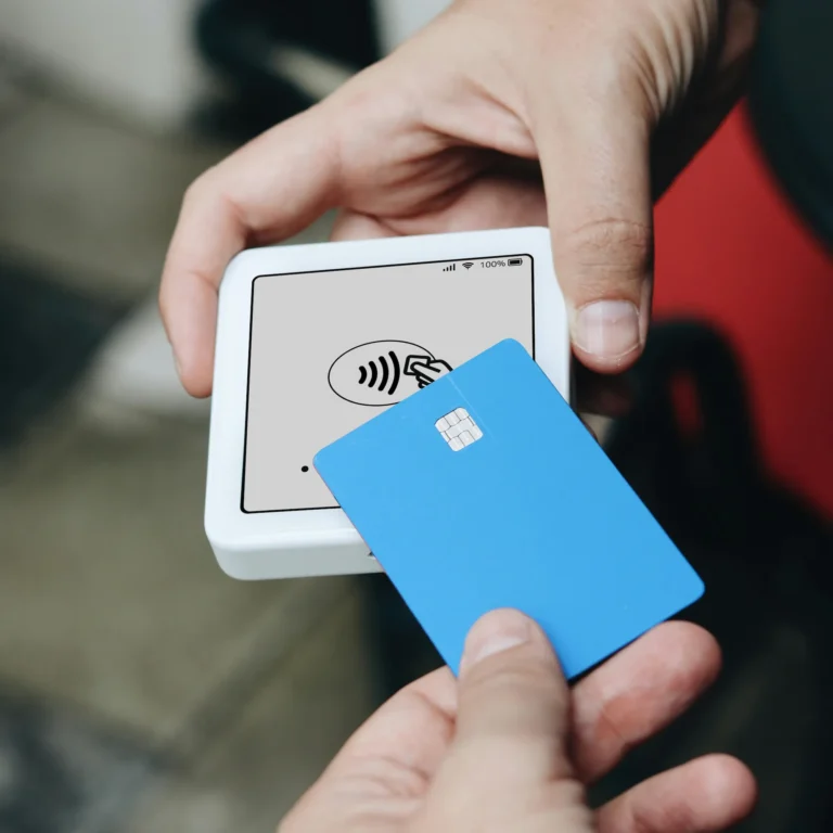 A person types on a laptop during a contactless card transaction, symbolizing FinTech Services driving innovation and growth in digital finance through seamless payments, secure technology, and user-friendly experiences.