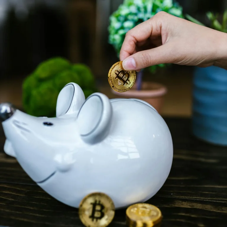 A hand places a Bitcoin coin into a mouse-shaped piggy bank surrounded by digital currency, symbolizing Future Business Bank powered by AI, blockchain, and digital finance innovation.