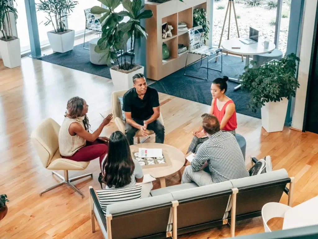 A group of professionals collaborate around a round table in a modern office, symbolizing SBA Loans for Outsourcing Expansion, financial support that helps businesses scale with confidence through strategic partnerships and operational growth.