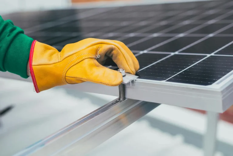A worker installs a solar panel with protective gloves, symbolizing renewable energy adoption supported by Solar Incentives 2026 tax credits and rebates driving growth.