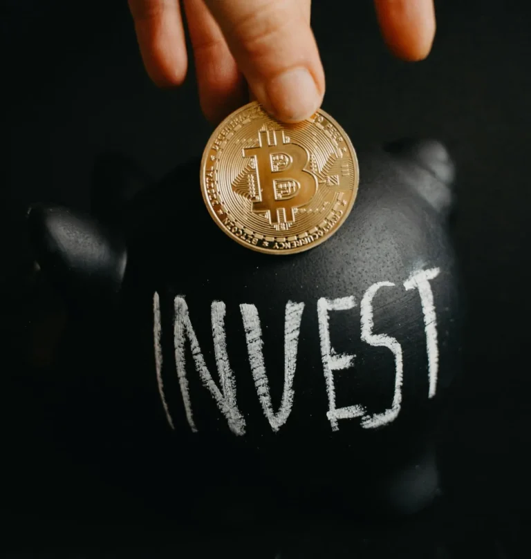 A hand places a Bitcoin coin into a piggy bank labeled INVEST, representing the Stock Market and the algorithmic era where AI, retail investors, and global events drive digital-asset investment decisions.
