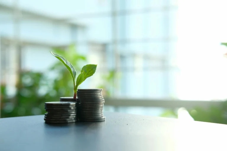 Stacks of coins with plant sprouts symbolize growth and Business Automation benefits for small businesses.