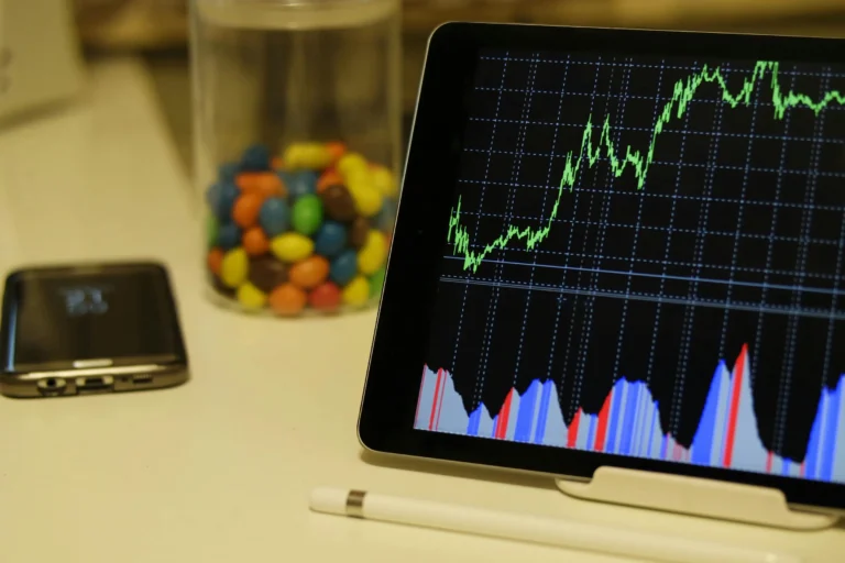 A tablet displays financial charts beside a smartphone and stylus, illustrating what is a FinTech company in action.
