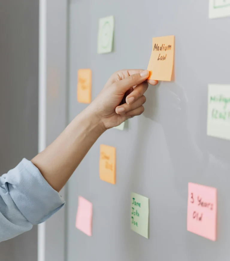 A hand places a sticky note on a colorful board during a planning session, symbolizing Cryptocurrency Funding Trend as a dynamic flow of capital shaping growth strategies through collaborative forecasting and decentralized innovation.