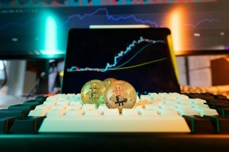 Bitcoin coins rest on a keyboard with trading charts on nearby screens, symbolizing Cryptocurrency Marketing Insights that build trust and growth through visual branding, bullish signals, and digital engagement strategies.
