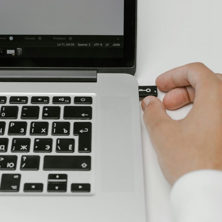 A close-up of a person inserting a USB security key into a laptop with Cyrillic keyboard, while a JSON file is open on the screen, symbolizing Advanced Cybersecurity Systems Protecting Digital Assets through hardware-based authentication, secure coding environments, and multi-layered access control that safeguard sensitive data in global tech infrastructures.