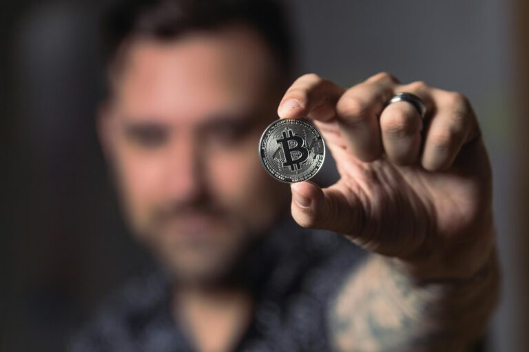 A person holds a silver Bitcoin coin with circuit-like engravings, symbolizing Bitcoin as a Growth Asset for Investors through digital scarcity, decentralized value storage, and long-term capital appreciation in modern financial portfolios.