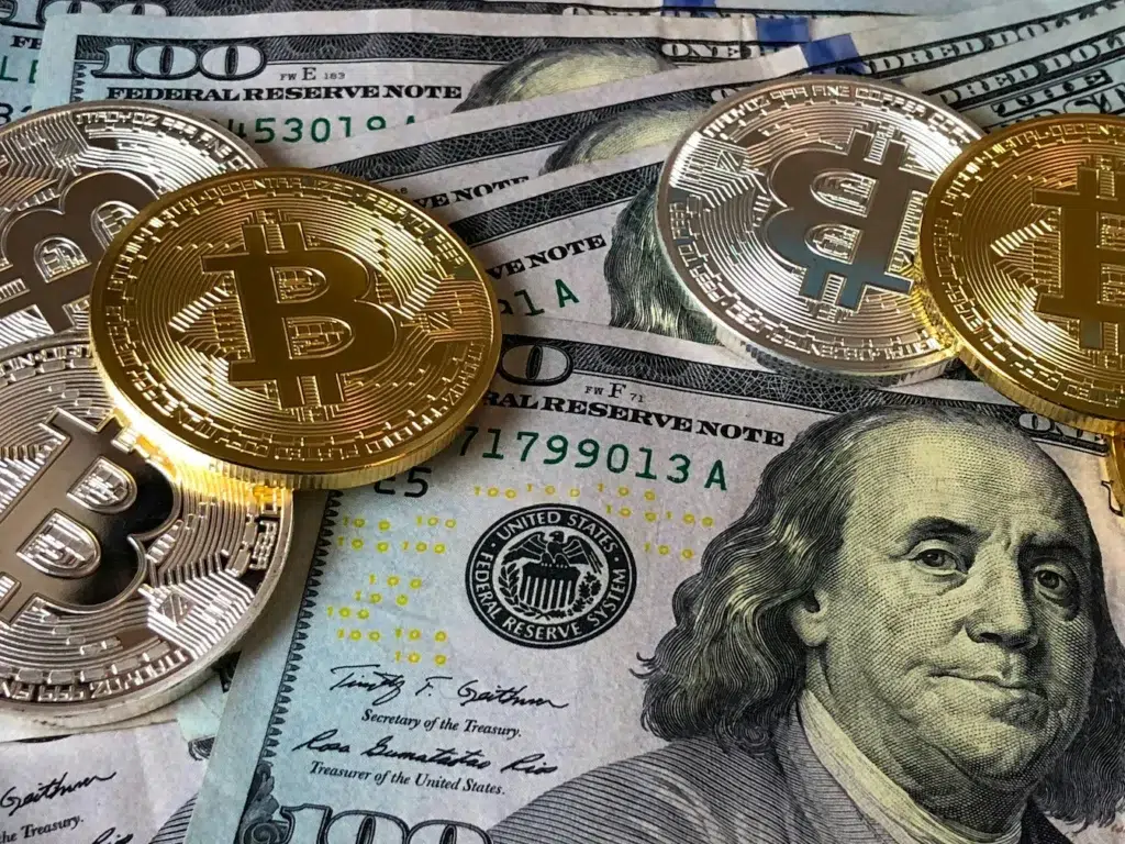 Metallic Bitcoin coins rest atop U.S. $100 bills, symbolizing Crypto Payroll for Remote Teams: Global Payments Made Simple through the fusion of decentralized finance and traditional currency, enabling seamless cross-border compensation, financial flexibility, and modern payroll solutions for global teams.