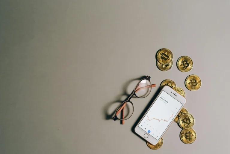 A smartphone displays a financial graph with a value of €25,511.90 alongside Bitcoin tokens and eyeglasses on a neutral surface; symbolizing Cryptocurrency Assets for Scaling Global Growth through digital wealth tracking, decentralized finance tools, and visual cues of investor readiness in a globalized financial ecosystem.