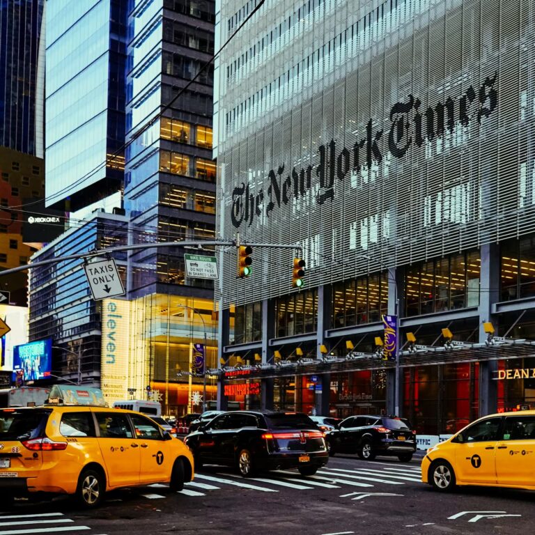 A bustling New York City street scene featuring The New York Times headquarters, yellow taxis, and active traffic; symbolizing Economic Growth Strategies for Global Competitiveness through urban infrastructure, media influence, and dynamic commercial activity that reflect the interconnected forces driving innovation, investment, and strategic positioning in global markets.