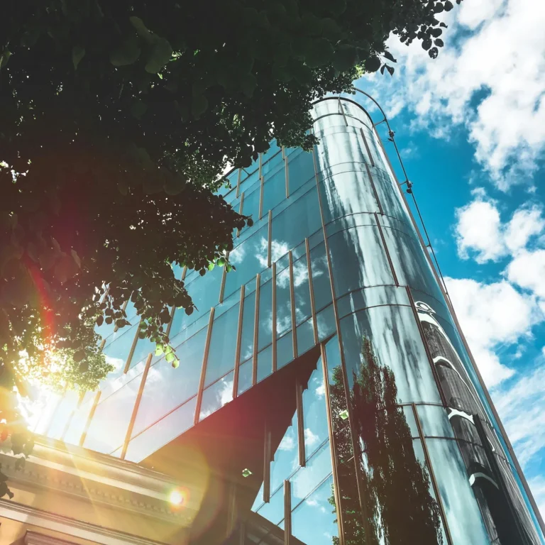 A modern glass building with a curved facade reflects the sky and trees, symbolizing Entrepreneur Loans for Growth Building Business Resilience through transparent financial infrastructure, sustainable business development, and the integration of nature and innovation in entrepreneurial ecosystems