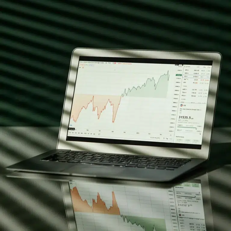 A laptop displays a Dow Jones chart with red and green trend lines, symbolizing Fintech Financial Solutions for Scaling: Unlocking Efficiency through real-time market insights, data-driven decision-making, and digital tools that support financial growth.