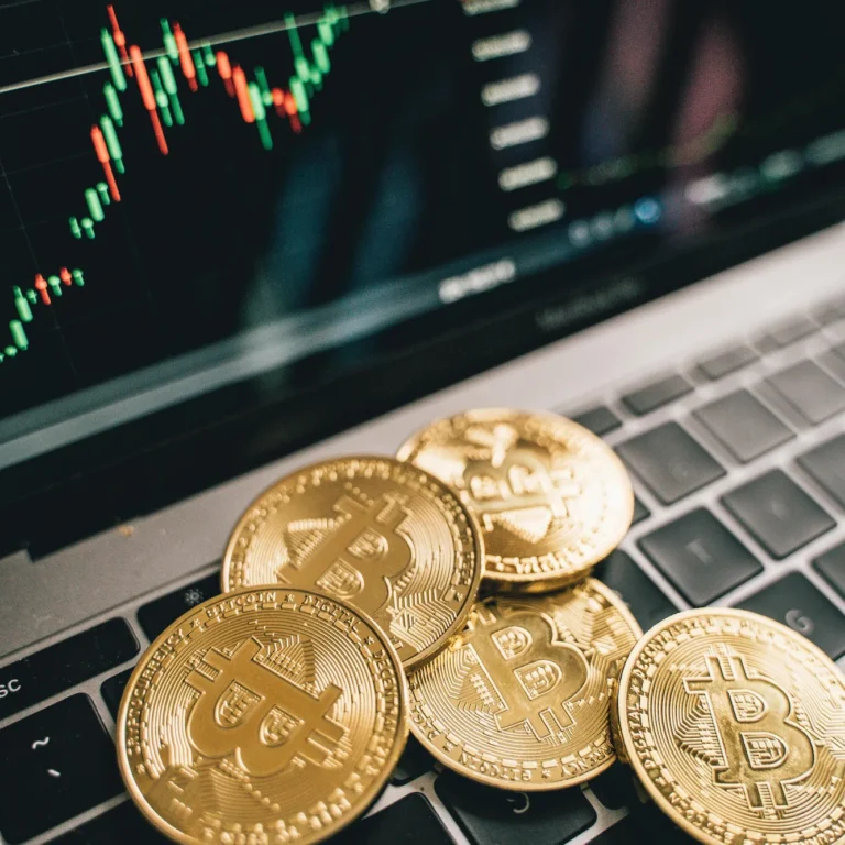 Bitcoin coins rest on a laptop keyboard with a candlestick chart on screen, symbolizing the Future of Cryptocurrency Tech Innovations through digital assets, market analytics, and evolving blockchain-driven financial systems.