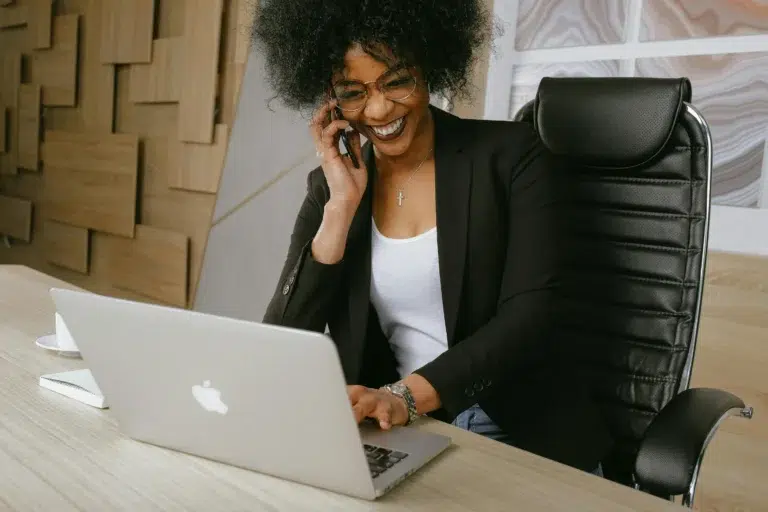 A professional multitasks at a desk, speaking on the phone while working on a laptop, symbolizing Industry Productivity Trends: Driving Efficiency Across Sectors through agile communication, digital tools, and modern workplace adaptability.