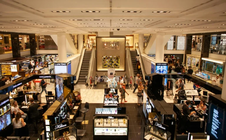 A bustling luxury department store showcases branded counters like Louis Vuitton, Estée Lauder, and Dolce & Gabbana, with shoppers navigating escalators and vibrant displays; symbolizing Loans for Marketing Growth Driving Expansion through high-impact retail visibility, consumer engagement, and strategic funding that fuels brand elevation and market reach.