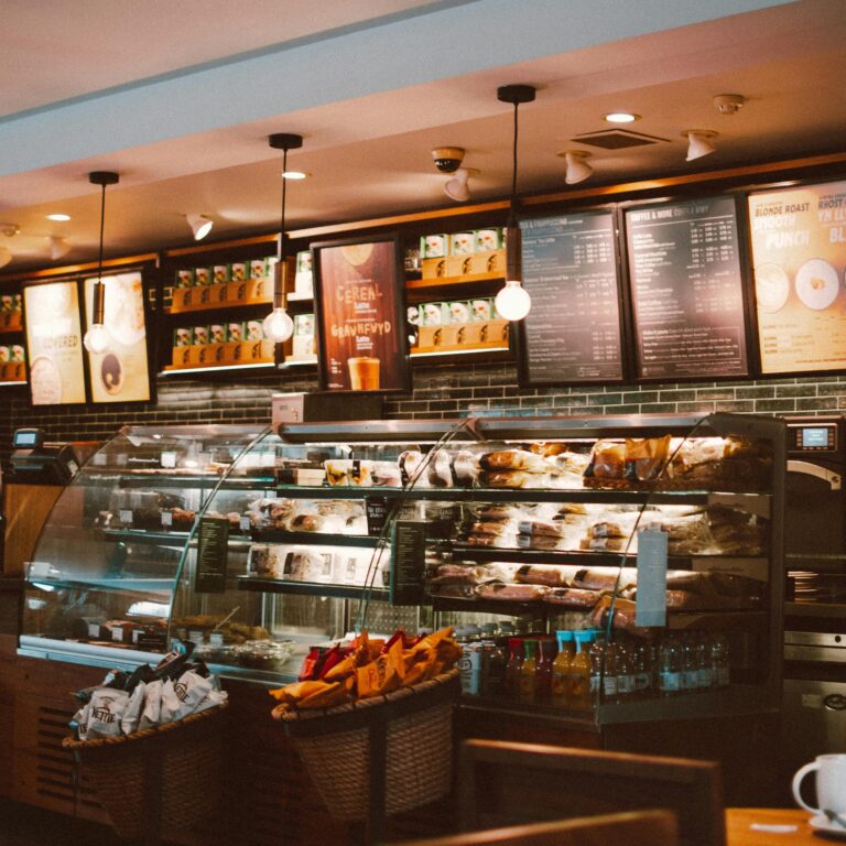 Interior of a cozy café with a glass display of baked goods, bottled drinks, and menu boards overhead, symbolizing SBA Loans for Expansion Strategies through small business growth, retail upgrades, and funding support that enable entrepreneurs to scale operations and enhance customer experience.