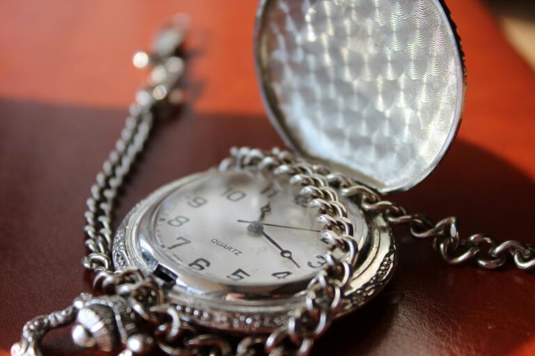 Close-up of a silver pocket watch with chain resting on a reddish surface, symbolizing Silver Price Analytics for Smarter Investments through precision, timeless value, and the strategic tracking of silver assets as part of diversified investment portfolios.