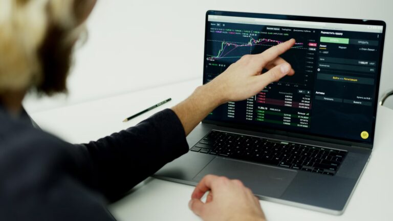 A person analyzing cryptocurrency charts on a laptop, symbolizing Stock Market Automation Driving Investor Advantage through real-time trading tools.