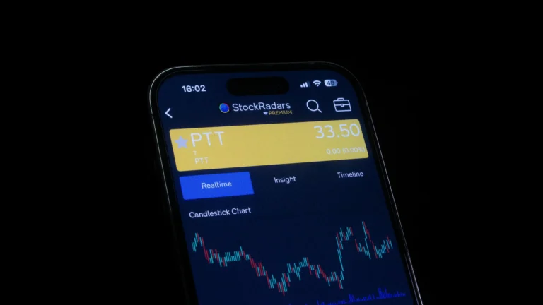A smartphone screen displays the StockRadars PREMIUM app with a candlestick chart for PTT stock priced at 33.50, alongside tabs for “Realtime,” “Insight,” and “Timeline”, symbolizing Stock Market Tech Innovations Driving Investor Growth through mobile analytics, real-time data access, and intuitive trading platforms that empower investors to make informed decisions and scale portfolio performance.
