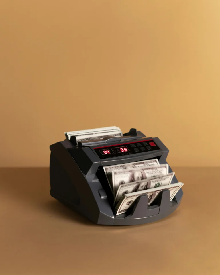 A currency counting machine processes stacks of U.S. $100 bills; symbolizing US Bank Fintech Innovations Transforming Finance through automation, precision cash handling, and digital infrastructure that modernizes financial operations and enhances efficiency across banking ecosystems.