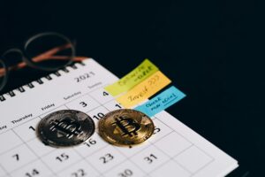 Two physical Bitcoin coins rest on a January 2021 calendar page, placed over the dates January 8 and 10, surrounded by handwritten sticky notes reading “Optimize wallet,” “Invest???,” and “Check new coins,” with eyeglasses partially visible, symbolizing Bitcoin Long-Term Investment The 2026 Reserve Pillar through strategic planning, portfolio optimization, and milestone tracking that empower founders and investors to build resilient crypto reserves, align with macroeconomic cycles, and shape future-proof digital asset strategies.