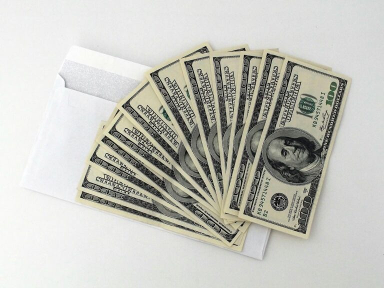A white envelope partially opened to reveal ten U.S. $100 bills fanned out, symbolizing Funding Scale via the 2026 Stock Market Expansion through capital access, liquidity growth, and financial momentum driven by equity markets, investor confidence, and scalable funding strategies.
