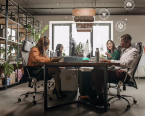 Four professionals collaborate around a desk in a modern, plant-filled office with headsets and computers, surrounded by digital overlay icons of health, sustainability, and productivity, symbolizing Industry Workplace Wellness Trends for Business Growth through tech-enabled collaboration, eco-conscious design, and founder-led wellness strategies that empower organizations to boost employee engagement, align culture with performance, and scale growth through holistic workplace innovation.