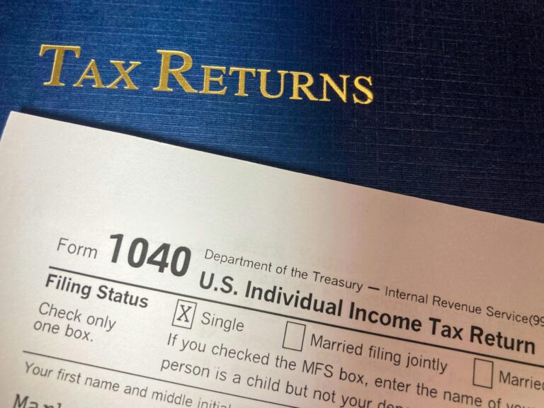 A partially filled U.S. Form 1040 with the “Single” filing status box checked sits beside a blue folder embossed with “TAX RETURNS” in gold, symbolizing Maximize Tax Refunds with Smart Strategies through proactive filing, deduction planning, and founder-led financial optimization that empower individuals and entrepreneurs to streamline compliance, unlock refund potential, and align tax strategy with long-term wealth goals.