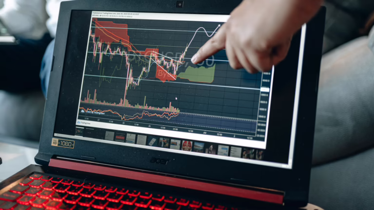 A hand points to a Bitcoin-to-USD trading chart on a laptop screen using the TradingView platform, featuring candlestick patterns, volume bars, Ichimoku cloud zones, and a projected price path, symbolizing Fintech Software Platforms Powering Digital Finance Growth through real-time analytics, technical charting tools, and founder-led fintech infrastructure that empower traders, analysts, and platforms to decode market signals, optimize digital asset strategies, and scale financial innovation across global ecosystems.