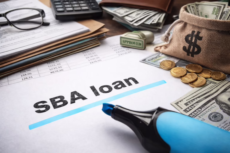 A financial workspace features a document labeled “SBA loan” marked with a blue highlighter, surrounded by a burlap sack with a dollar sign, gold coins, U.S. bills, a rubber stamp reading “APPROVED,” a credit card, calculator, eyeglasses, and spreadsheets with numerical data, symbolizing SBA Loan Eligibility for Small Business Growth through founder-led funding strategies, financial documentation, and government-backed support systems that empower entrepreneurs to access capital, scale operations, and build resilient business models.