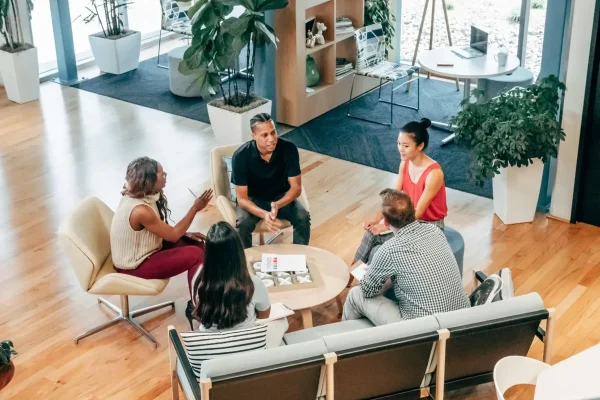 A group of professionals collaborate around a round table in a modern office, symbolizing SBA Loans for Outsourcing Expansion, financial support that helps businesses scale with confidence through strategic partnerships and operational growth.